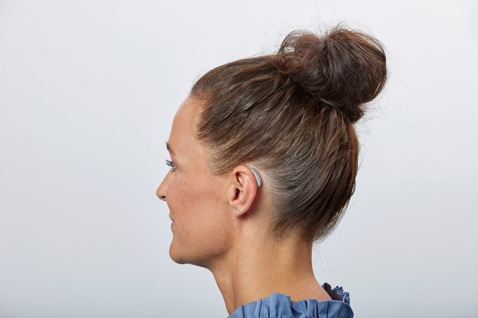 A discreet behind-the-ear hearing aid being worn